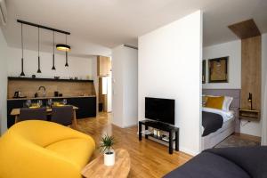 a living room with a yellow chair and a bedroom at Studio Apartman KRILA WINGS in Zagreb