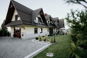 una grande casa bianca con tetto nero di Nocleg Pod Gubałówką a Nowe Bystre