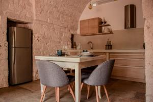 a kitchen with a table and chairs and a refrigerator at Trullo Genesi in Cisternino