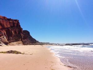 a sandy beach with rocks and the ocean at FreeSurfCamp & Hostel in Peniche