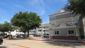 un edificio de apartamentos con coches aparcados en un aparcamiento en InTown Suites Extended Stay Arlington TX – South, en Arlington