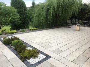 un jardín con un patio de piedra y árboles en Silver Residence en Rabka