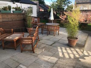 a patio with wooden chairs and tables and an umbrella at The Dalbury and Palmer Hotel with FREE PARKING in Sheffield