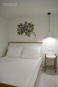 a bedroom with a white bed with a plant on the wall at Haraki Endless Blue Luxury Apartments in Haraki