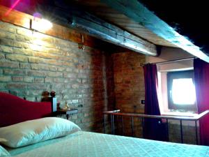 1 dormitorio con pared de ladrillo y 1 cama con ventana en Casa Lombardi en Ovindoli