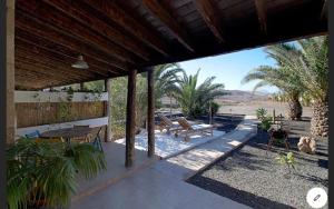 eine Terrasse mit Tischen, Stühlen und Palmen in der Unterkunft Finca Arbequina in Pájara