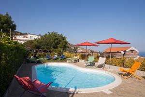 a swimming pool with lawn chairs and umbrellas at Villa Li Galli in SantʼAgata sui Due Golfi