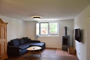 a living room with a blue couch and a tv at Gästehaus Palli in Unterdietfurt