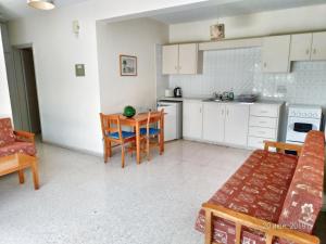 cocina con armarios blancos, mesa y sillas en Constantaras Apartments, en Protaras