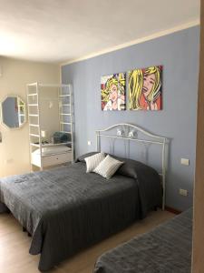 um quarto com duas camas e pinturas na parede em Irides rooms em Lazise