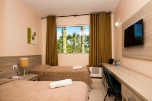 um quarto de hotel com duas camas e uma janela em Hotel Golden Park Campos do Jordão em Campos do Jordão