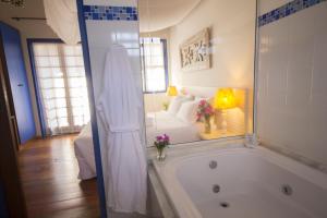 a bathroom with a tub and a bedroom with a bed at Pousada Vivenda in Tiradentes