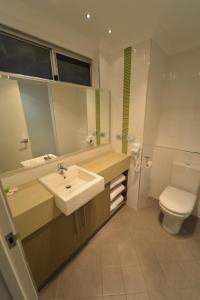 a bathroom with a toilet, sink, and mirror at Bentley Motel in Perth
