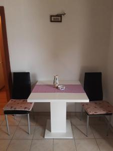 馬斯林尼采的住宿－Lilo，一张带两把椅子的白色桌子和花瓶