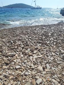a rocky beach with a boat in the water at Lilo in Maslinica