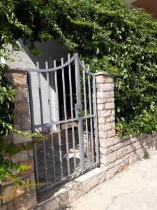 una puerta de metal en una pared de piedra con arbustos en Lilo, en Maslinica