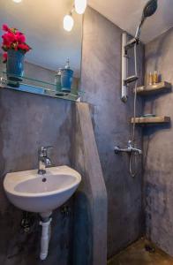 a bathroom with a sink and some flowers on a shelf at BLUE PARADISE SUITES in Pachaina