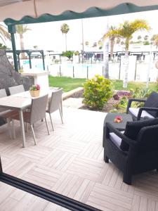 een patio met een tafel en stoelen en de oceaan bij Renovated House Front-Pool in Maspalomas