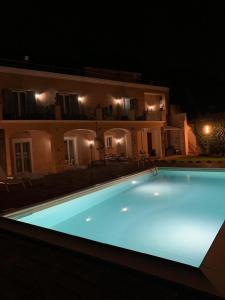 a swimming pool in front of a house at night at B&B Villa Etelka in Aci Castello