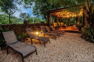 a row of chairs and a patio with a stone wall at Hacienda Guachipelin Volcano Ranch Hotel & Hot Springs in Liberia