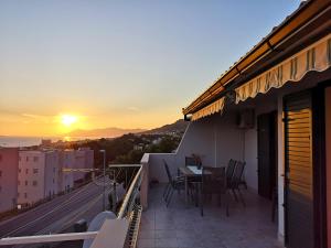 balcón con mesa, sillas y vistas a la puesta de sol en Villa Oliva, en Makarska