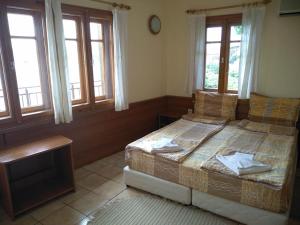 a bedroom with two beds and a table and windows at Guestrooms Durna in Sozopol