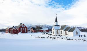 a church in a snow covered field with a church at Tranøya in Tranøya
