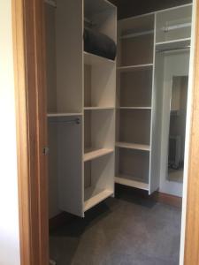 a walk in closet with white shelves and a door at Lansdown Peaks Apartments in Wanaka