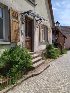 Casa con puerta de madera y calle de ladrillo en La Grande Terrine - Gîtes Les Potiers, en Kaysersberg