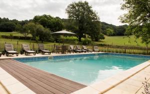 uma piscina com cadeiras e um guarda-sol em Château de Valette em La Bachellerie