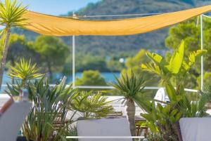 een patio met stoelen en palmbomen en een geel gordijn bij Beach Inn in Port d'Alcudia