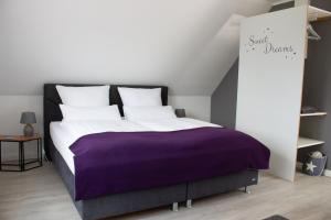 a bedroom with a large bed with a purple blanket at Heideträume Appartements in Undeloh