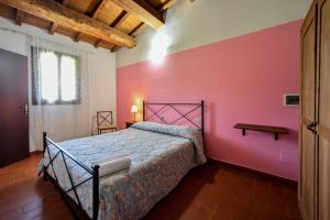 卡夏AGRITURISMO LA VALLE DEI BRONZETTI的一间卧室配有一张床和粉红色的墙壁