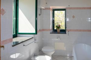 a white bathroom with a toilet and a window at B&B CASA VACANZA Cioffi in Vico Equense