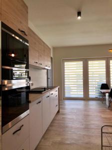 a large kitchen with white cabinets and black appliances at Apartament SŁONECZNY Pięć mórz Sianożęty in Sianozety