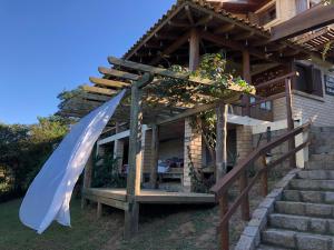 a wooden building with a porch and a white canopy at Hostel Vale do Rosa in Praia do Rosa