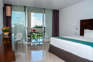 a bedroom with a bed and a table and a balcony at Mesón de la Luna Hotel & Spa in Mérida