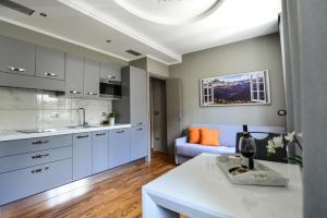 a kitchen with white cabinets and a living room at Altezza in La Morra