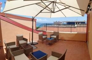 einen Balkon mit einem Tisch, Stühlen und einem Sonnenschirm in der Unterkunft La Conchiglia 2.0 in Soverato Marina