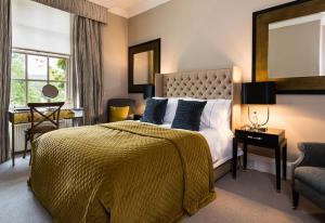a bedroom with a bed and a chair and a window at The Old Manse of Blair, Boutique Hotel & Restaurant in Blair Atholl