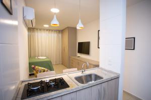 a kitchen with a sink and a living room at Flat Boa Viagem in Recife