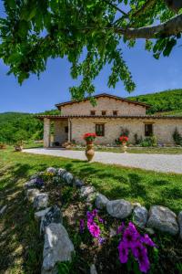 卡夏AGRITURISMO LA VALLE DEI BRONZETTI的石墙前有鲜花的房子