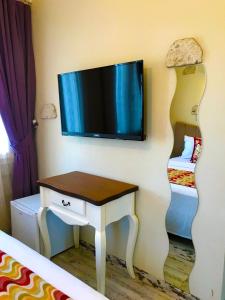 a room with a tv on a wall with a table at Alacati Viola Hotel in Alaçatı