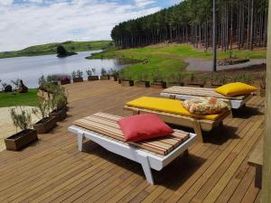 two benches sitting on a deck next to a body of water at Tedesco Eco Park in São Francisco de Paula