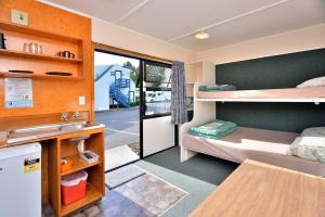 une petite chambre avec deux lits superposés et une cuisine dans l'établissement Auckland Northshore Motels & Holiday Park, à Auckland