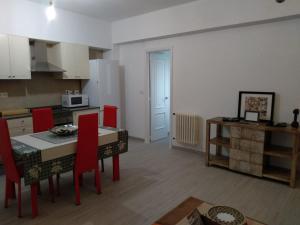 a kitchen and dining room with a table and red chairs at APARTAMENTO EN EL CENTRO DE LALIN in Lalín