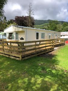 a mobile home with a wooden fence around it at 74 Glenfinart Caravan Park in Dunoon