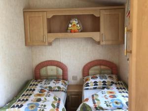 a bedroom with two beds and a cupboard at 74 Glenfinart Caravan Park in Dunoon