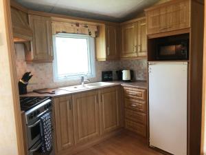 a kitchen with wooden cabinets and a white refrigerator at 74 Glenfinart Caravan Park in Dunoon