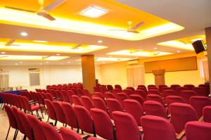 a conference room with red chairs and a podium at Sayoojyam Residency in Palakkad